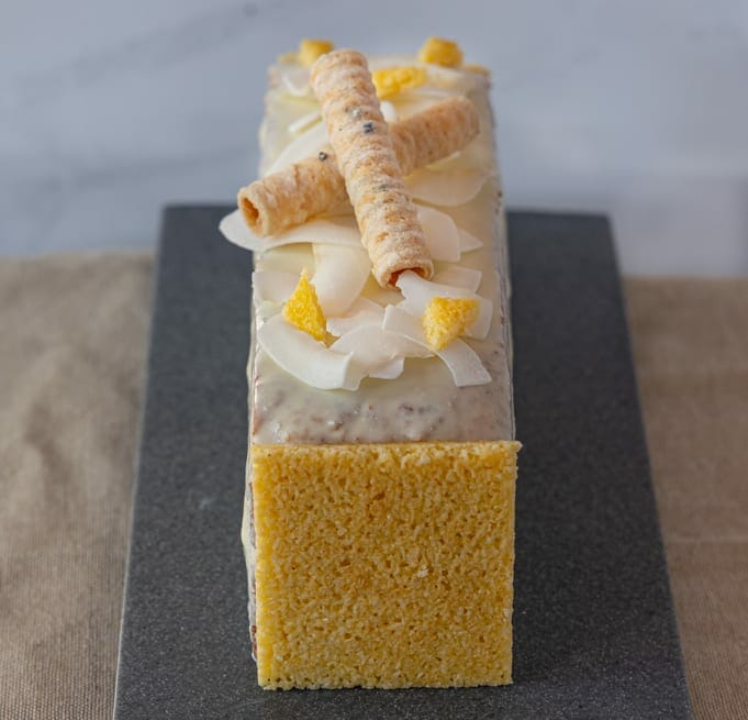 Travel Cake Caribbean, Coconut and Mango Flavour, decorated with coconut shaving enrolled in white chocolate-front view