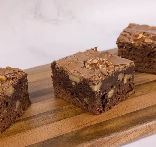 Three brownie slices on top of a wooden plate