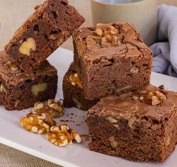 Brownies stacked on top of each other, with walnuts scattered around