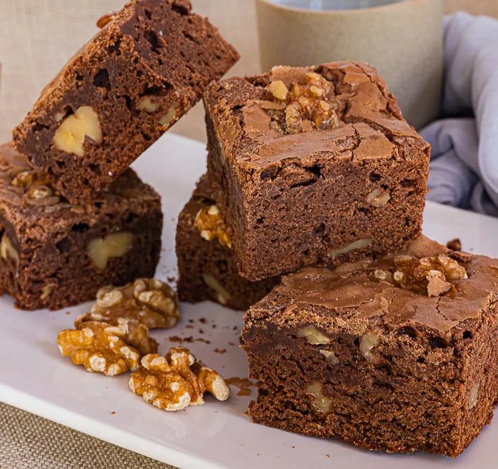 Brownies stacked on top of each other, with walnuts scattered around