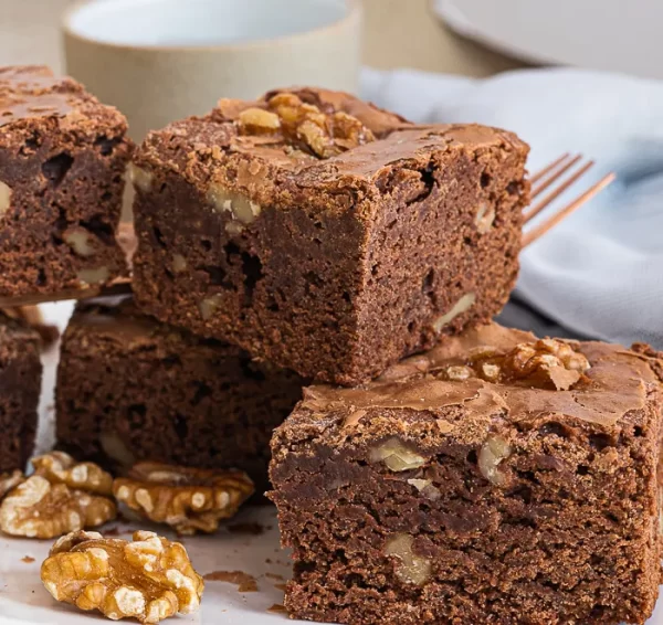 Brownies stacked on top of each other, with walnuts scattered around