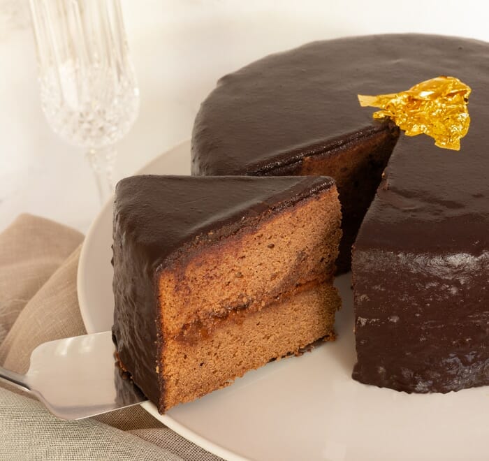 Chocolate Sacher cake with cut out of dessert portion and glass of champagne