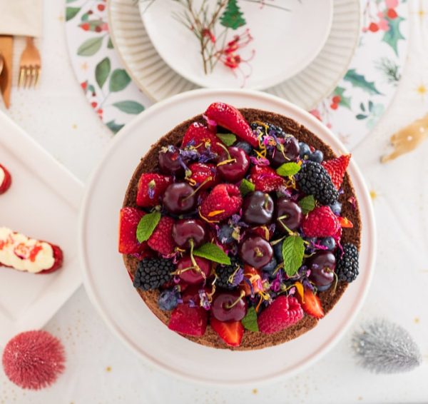 Raspberry Bavarois cake with berry fruits on top looking from above on table with Christmas decorations