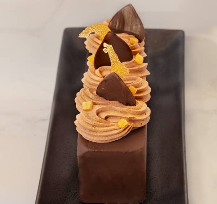 Travel Cake, Chocolate, Orange, Cardamom flavour, with chocolate and decoration on plate top front angle view