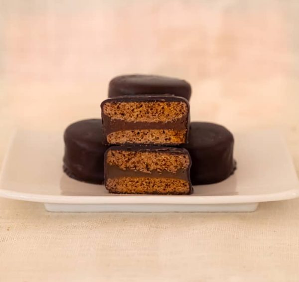Fore Alfajores on a place with on cut in half showing dulce de leche as the filling