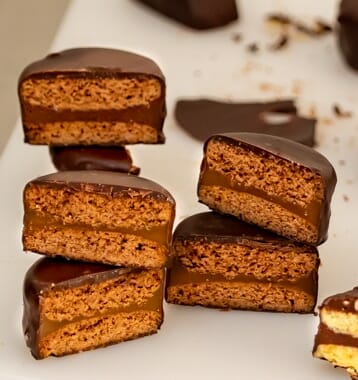 Alfajores with Dulce de Leche, cut in half, stacked on top of each other and chocolate crumbs in the background