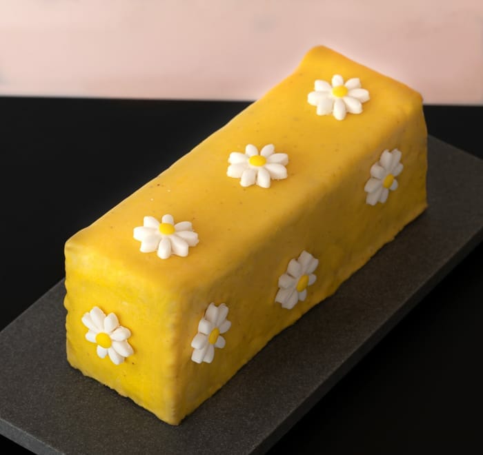 Just lemon travel cake on grey granite serving dish, with white daisies as decorations