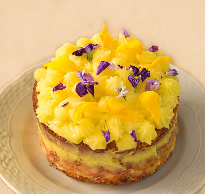 Lemon Mini Cake, on serving plate wth edible flowers on top as decoration