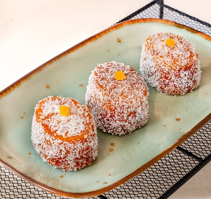 Three Petit four on serving plate, with coconut and mandarin decoration