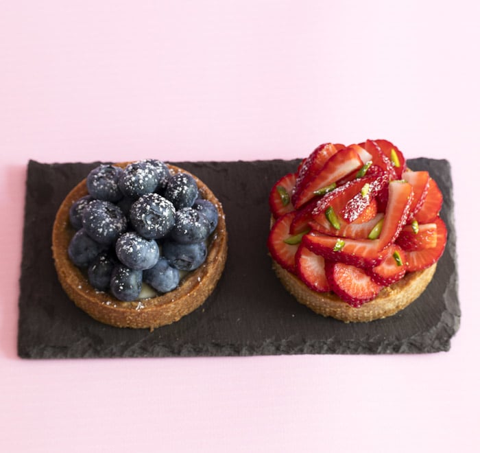 Two tarts, to left is bluberry and right the rasberry decorated at back,